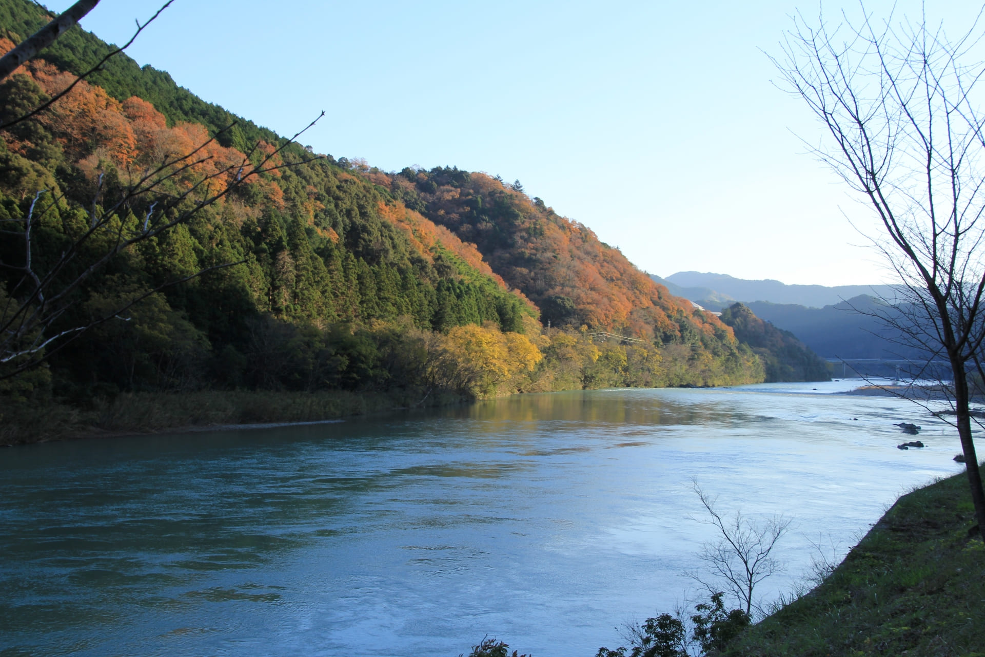 秋の四万十川。紅葉に染まった山々と穏やかな川面が広がる晩秋の風景
