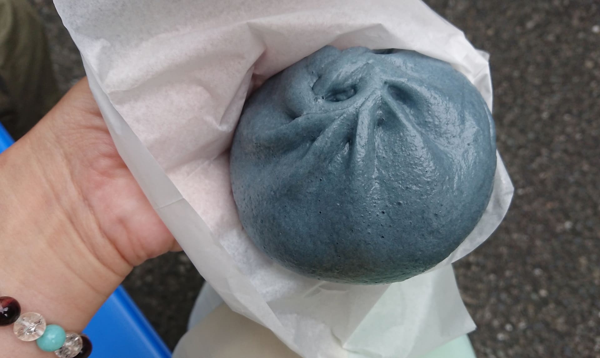 手のひらに乗った濃紺色のデニムまん。デニムの藍色を再現した生地に包まれた倉敷名物の食べ歩きグルメ