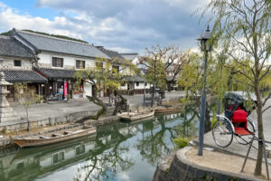 倉敷川沿いの美観地区。白壁の蔵屋敷が川に反射し、手前には赤い人力車が停まっている