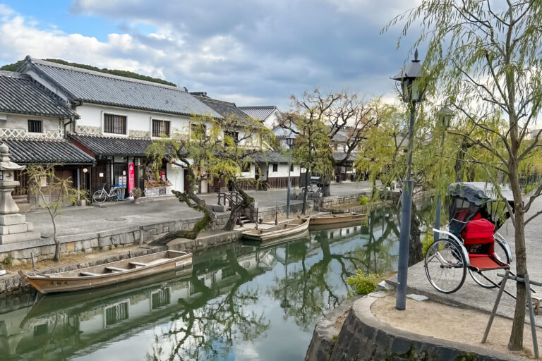 倉敷川沿いの美観地区。白壁の蔵屋敷が川に反射し、手前には赤い人力車が停まっている