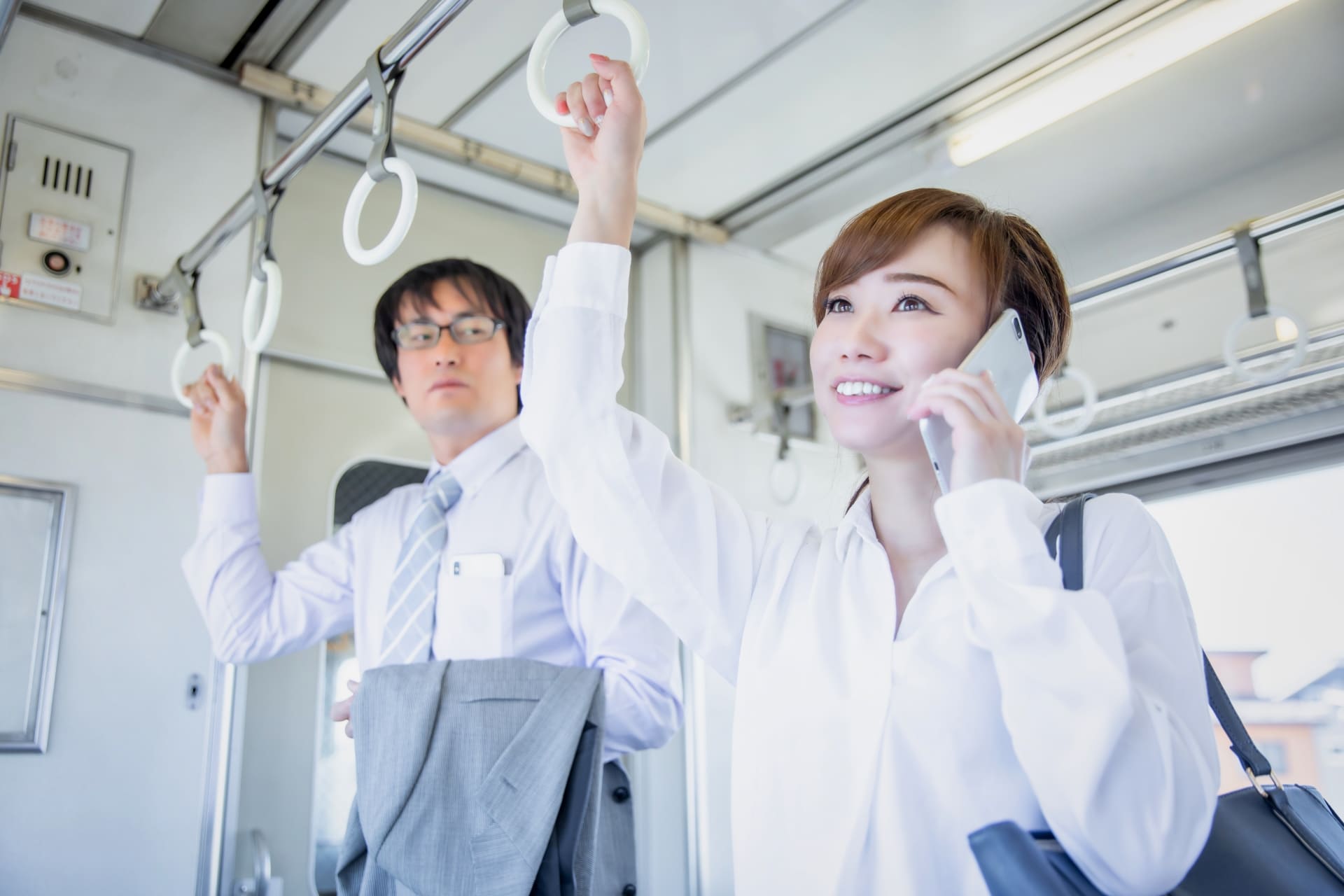 電車内で通話する女性と困惑した表情の男性